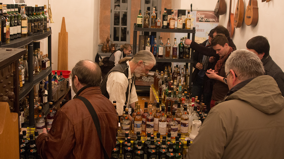 Blick auf einen Messe-Stand mit mehreren Gästen und vielen Whisky-Flaschen