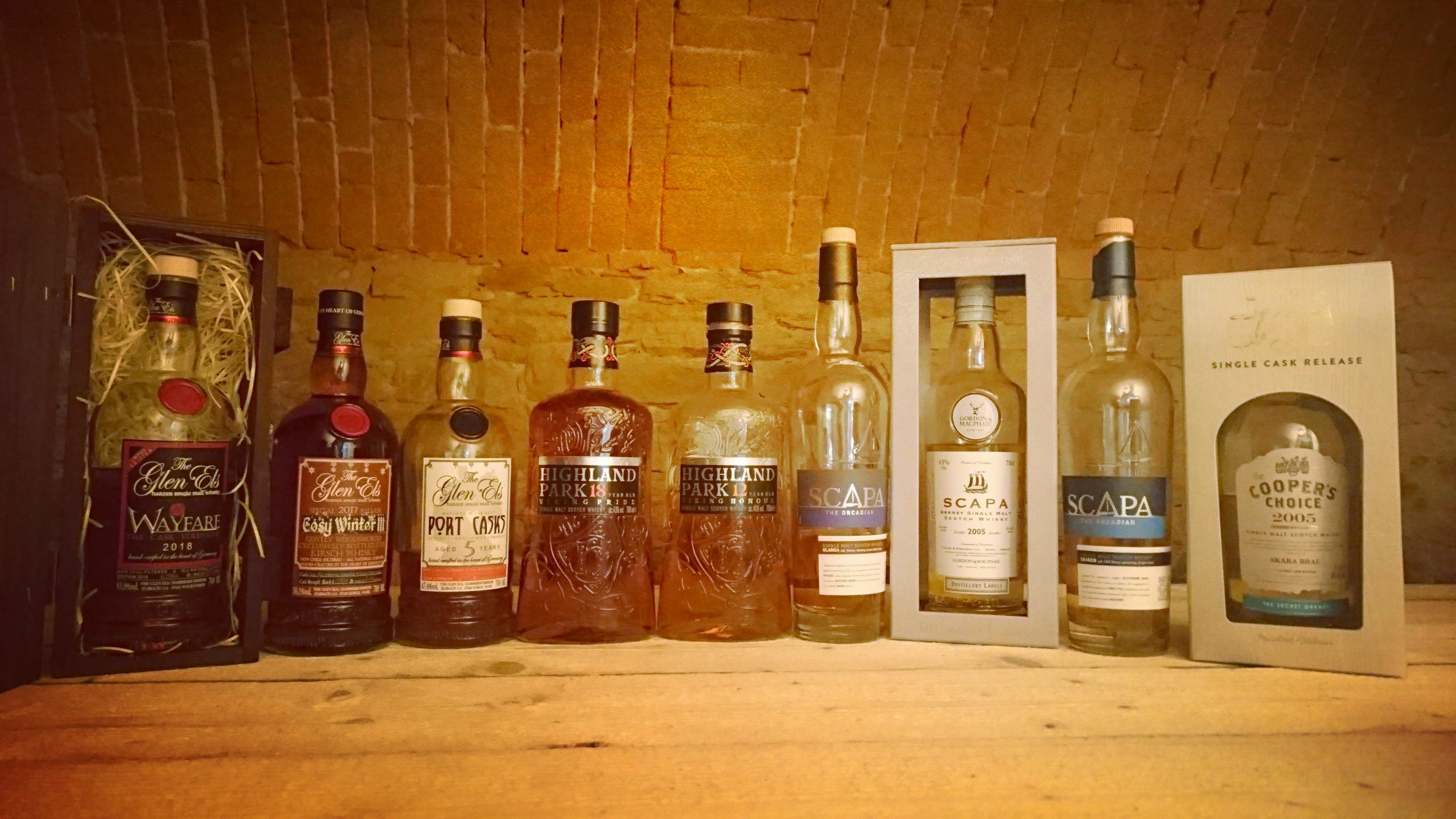 Neun verschiedene Whisky-Flaschen nebeneinander auf dem neuen Tisch im Gewölbekeller angeordnet
