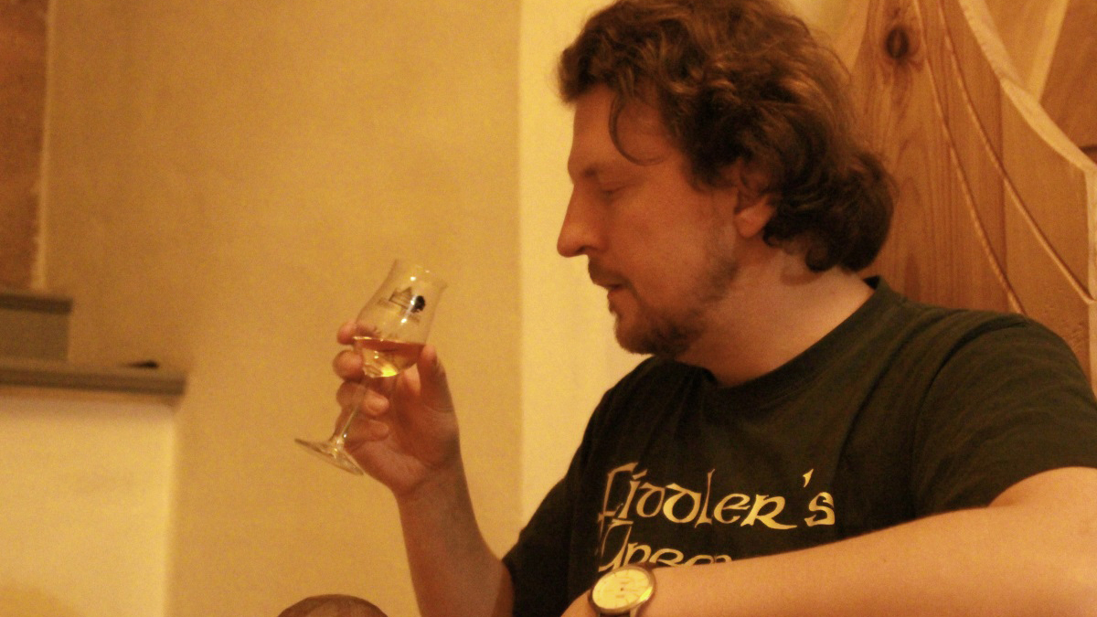 Ein Mann hält ein Nosing-Glas mit Whisky in seiner Hand